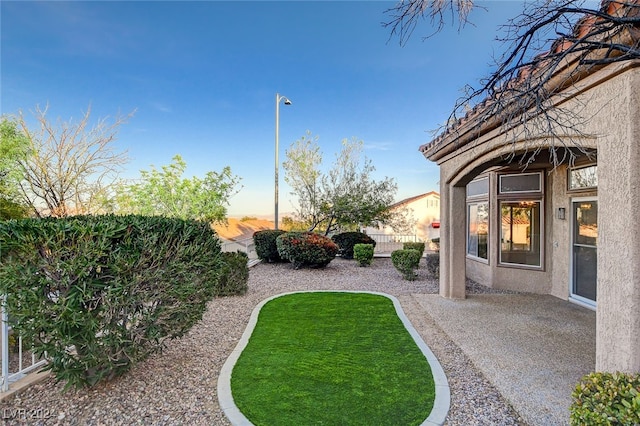 yard at dusk featuring a patio