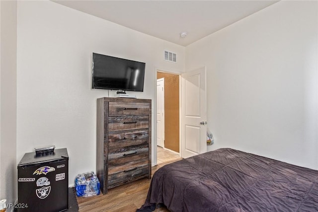 bedroom with baseboards, wood finished floors, and visible vents