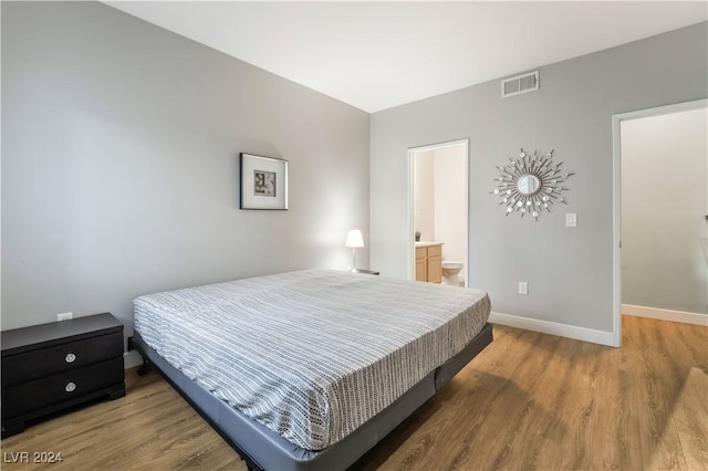 bedroom with connected bathroom and hardwood / wood-style floors