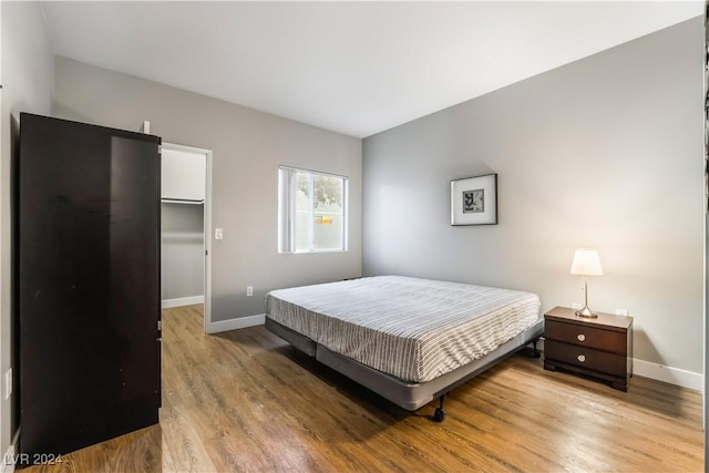 bedroom with wood-type flooring, a walk in closet, and a closet