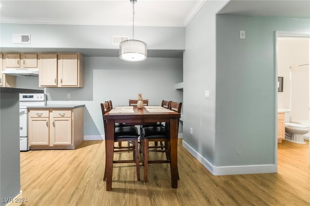 kitchen with light brown cabinets, hanging light fixtures, light hardwood / wood-style flooring, stove, and ornamental molding