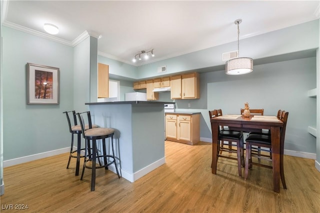 kitchen with light hardwood / wood-style flooring, kitchen peninsula, a kitchen bar, light brown cabinetry, and ornamental molding