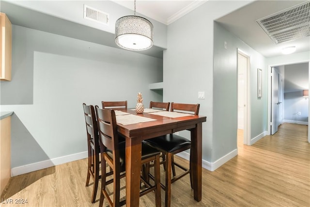 dining area with light hardwood / wood-style floors and crown molding