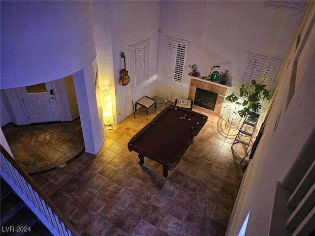 living room featuring a fireplace, a towering ceiling, and billiards