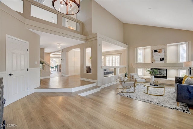 living room featuring light hardwood / wood-style flooring, high vaulted ceiling, and a chandelier