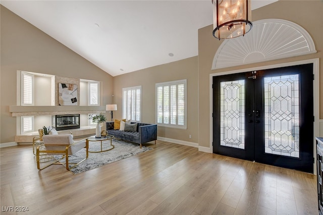 foyer featuring a chandelier, french doors, high vaulted ceiling, and light hardwood / wood-style floors