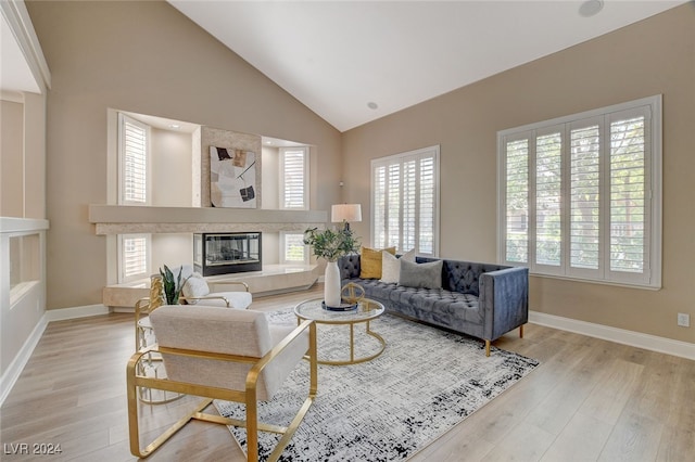 living room with a tile fireplace, high vaulted ceiling, and light hardwood / wood-style flooring