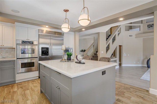 kitchen with a center island, gray cabinets, tasteful backsplash, light hardwood / wood-style floors, and stainless steel appliances