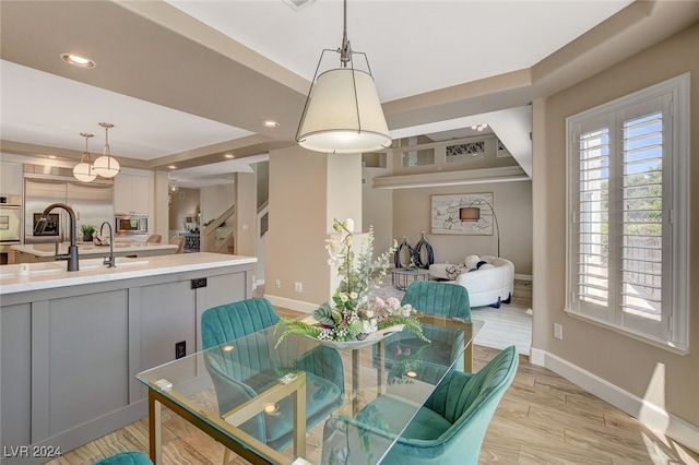 dining space with light wood-type flooring and sink