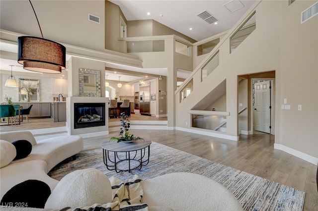 living room featuring light wood-type flooring, sink, and a high ceiling