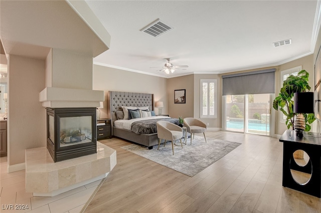 bedroom with access to exterior, ceiling fan, a multi sided fireplace, light wood-type flooring, and ornamental molding