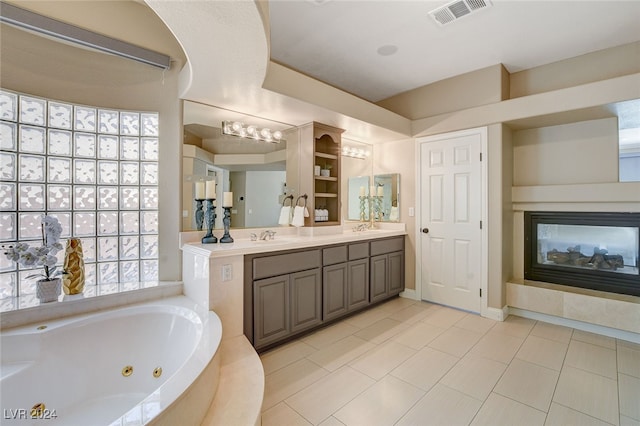 bathroom featuring vanity, tile patterned floors, plenty of natural light, and tiled tub