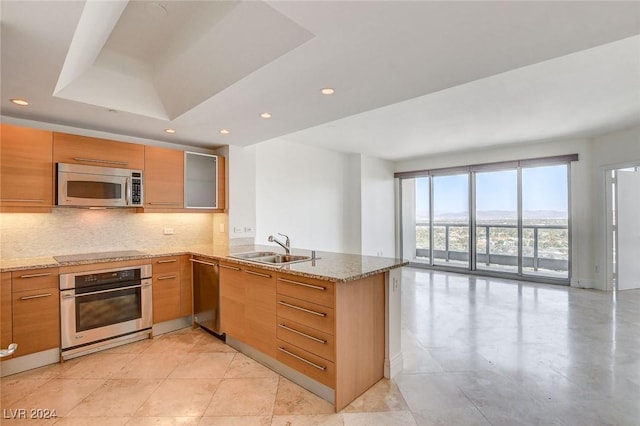 kitchen with kitchen peninsula, light stone counters, sink, and stainless steel appliances