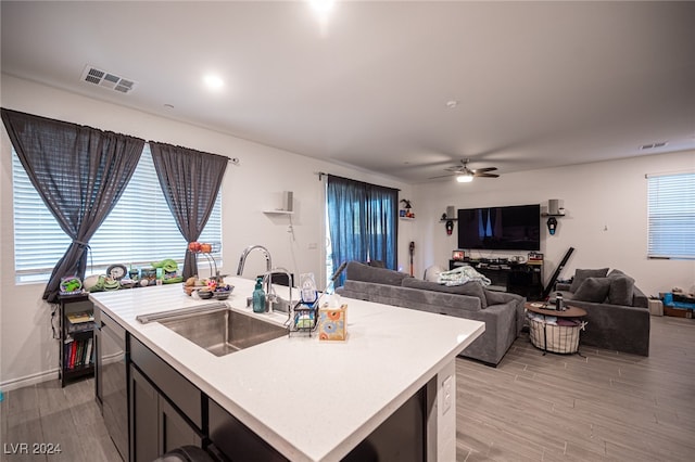 kitchen featuring ceiling fan, dishwasher, sink, an island with sink, and light wood-type flooring