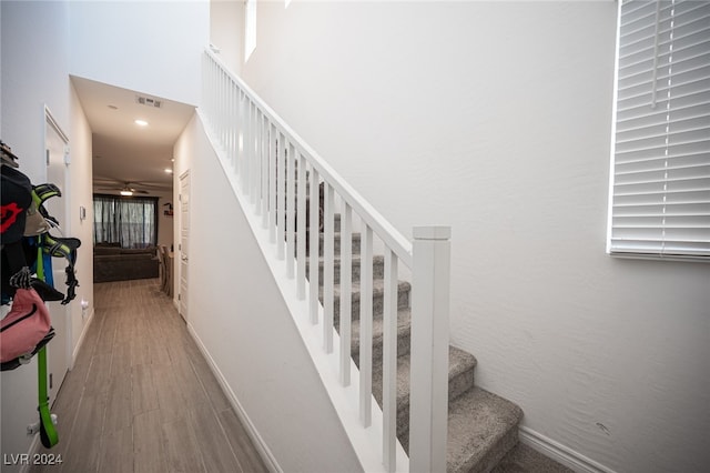 staircase with wood-type flooring and ceiling fan