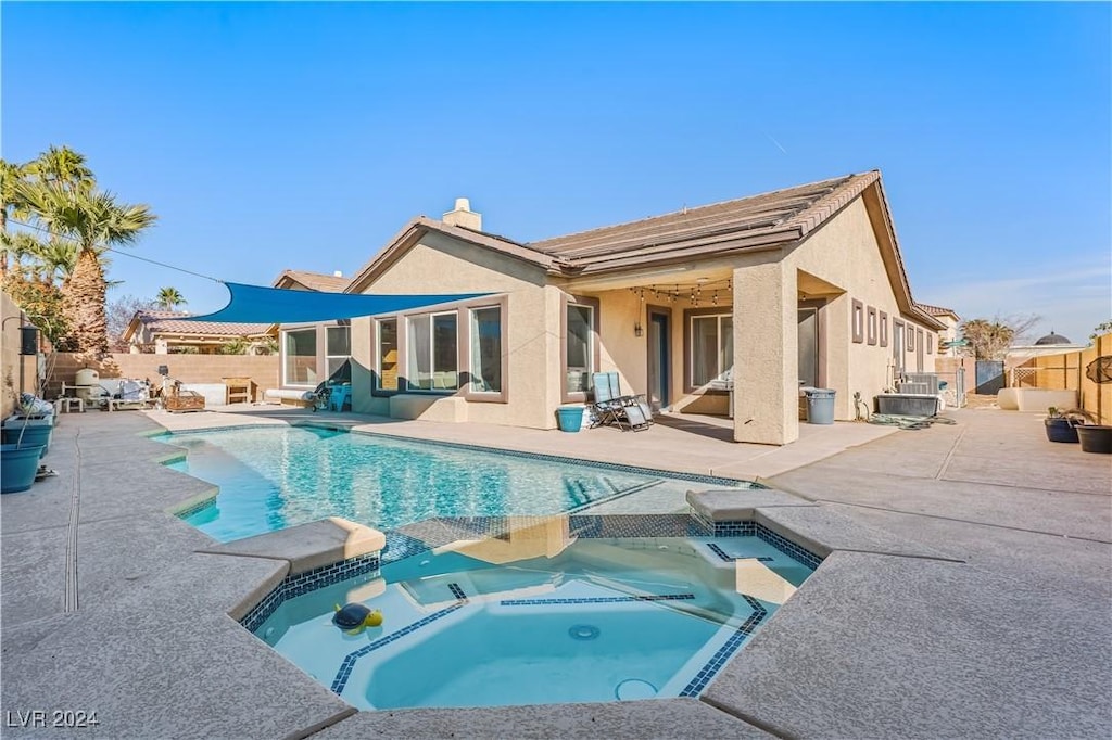 back of house featuring a patio and a pool with hot tub