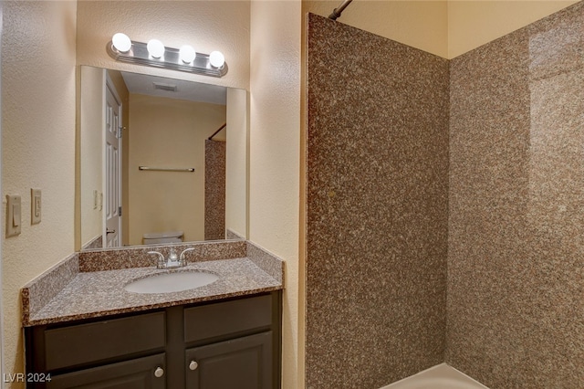 bathroom with visible vents, a textured wall, vanity, and toilet