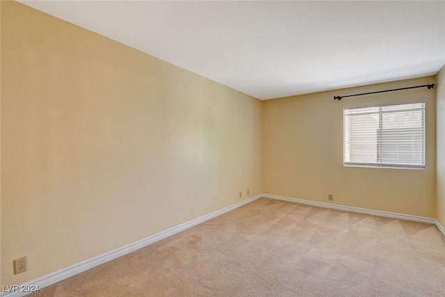 empty room featuring baseboards and light colored carpet