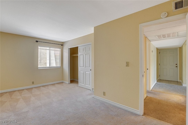 unfurnished bedroom with light carpet, a closet, visible vents, and baseboards