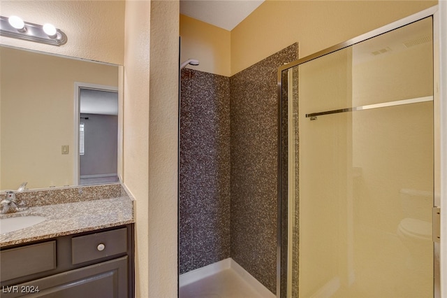 full bathroom featuring a textured wall, a shower stall, and vanity