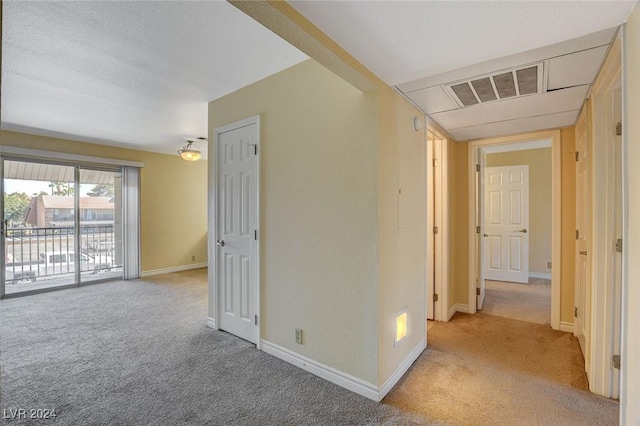 hall with carpet, visible vents, and baseboards