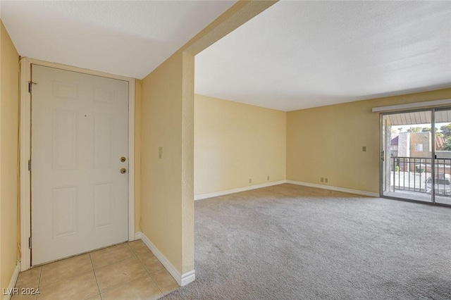 entryway featuring baseboards, light tile patterned flooring, and light colored carpet