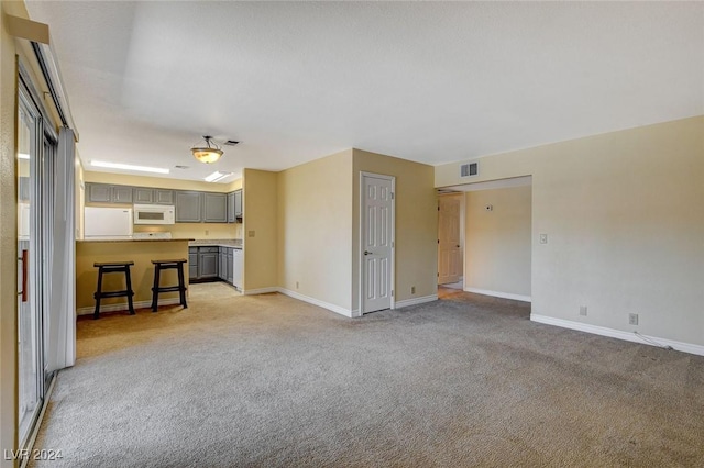 unfurnished living room featuring visible vents, light carpet, and baseboards