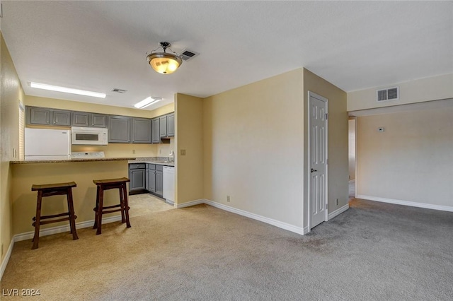 kitchen featuring light colored carpet, white appliances, visible vents, and gray cabinetry