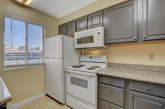 kitchen with gray cabinets, white appliances, light countertops, and baseboards