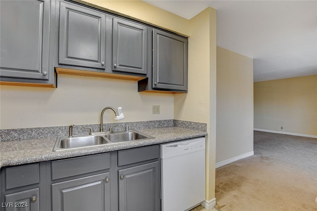 kitchen with baseboards, dishwasher, light colored carpet, gray cabinetry, and a sink