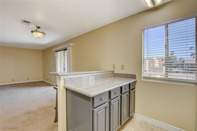 kitchen featuring gray cabinets, light countertops, visible vents, a peninsula, and baseboards