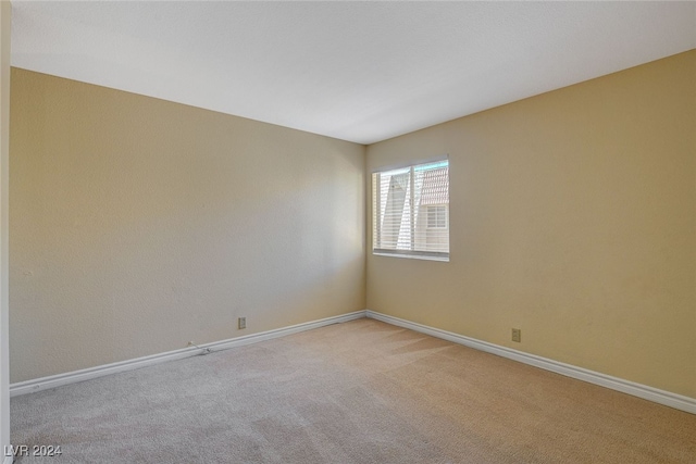 empty room featuring light carpet and baseboards