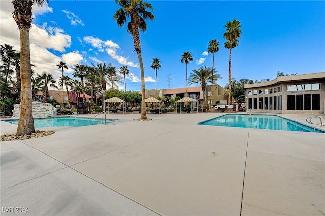 community pool with a patio and fence