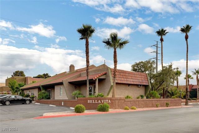 view of front of property featuring uncovered parking, a tiled roof, and stucco siding