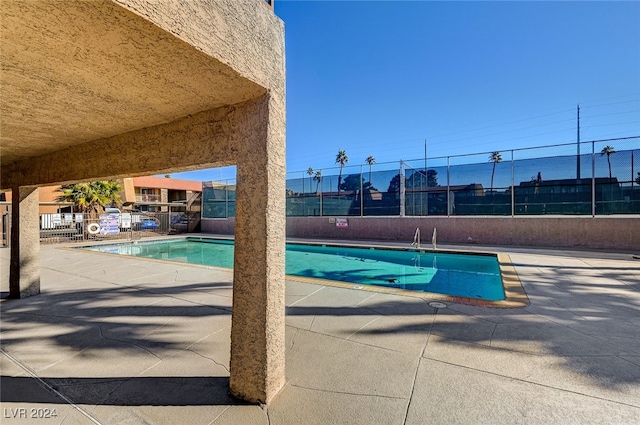 pool with a patio and fence