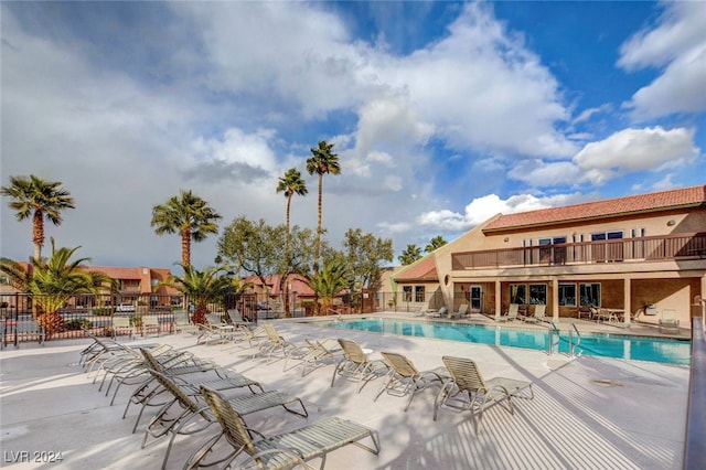 community pool with a patio area and fence