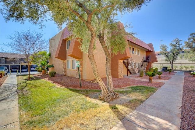 view of property exterior with stairway, a lawn, and stucco siding