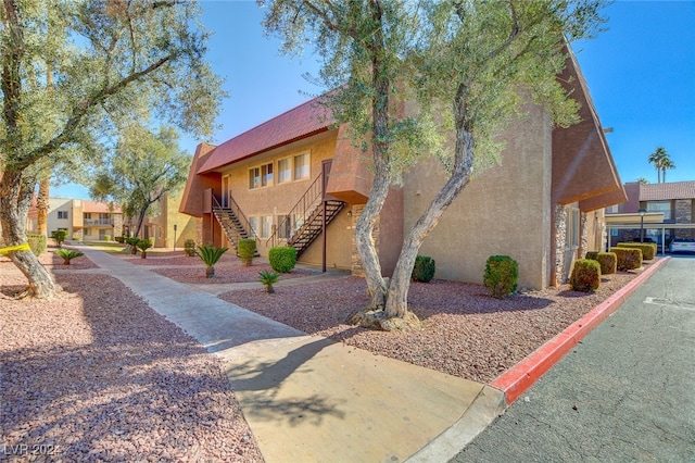 view of side of property featuring a residential view, stairway, and stucco siding