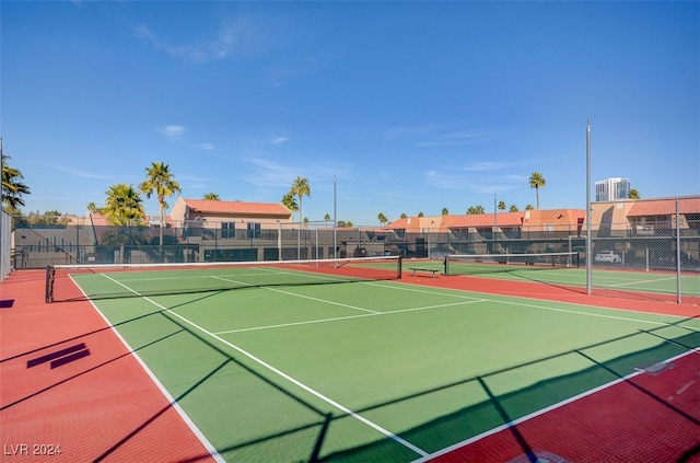 view of tennis court featuring community basketball court and fence