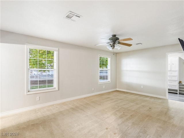 carpeted spare room featuring plenty of natural light and ceiling fan