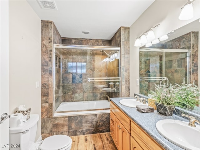 full bathroom featuring bath / shower combo with glass door, vanity, wood-type flooring, and toilet