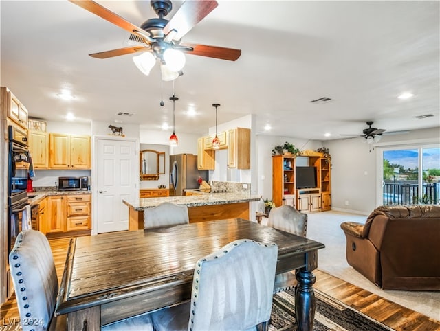 dining area with ceiling fan and light carpet