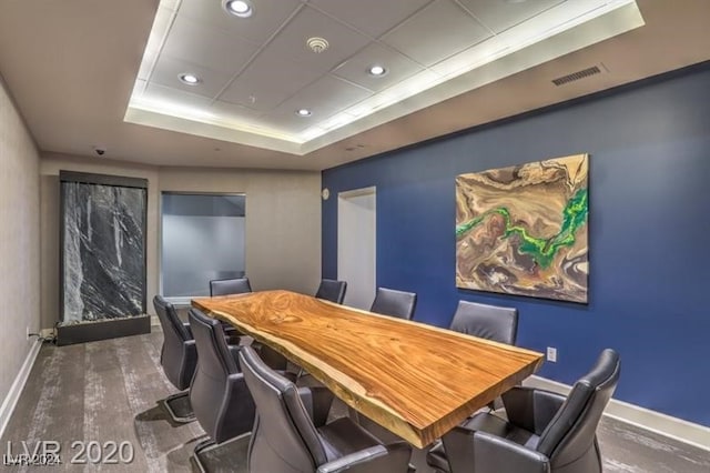 dining area with dark hardwood / wood-style floors and a raised ceiling