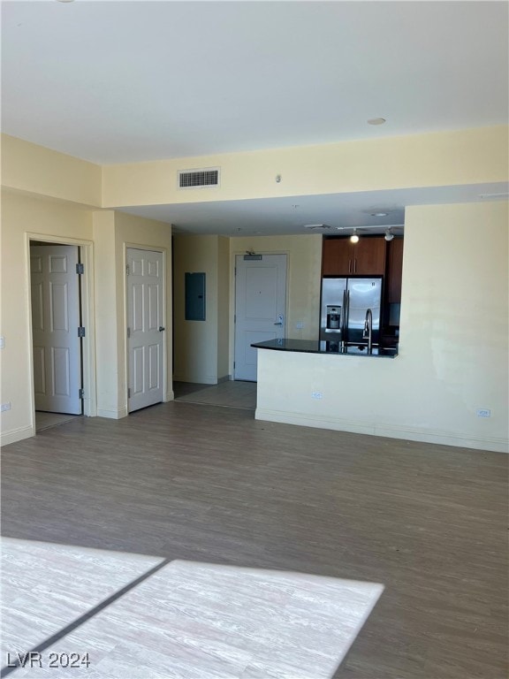 unfurnished living room with electric panel, sink, and light wood-type flooring