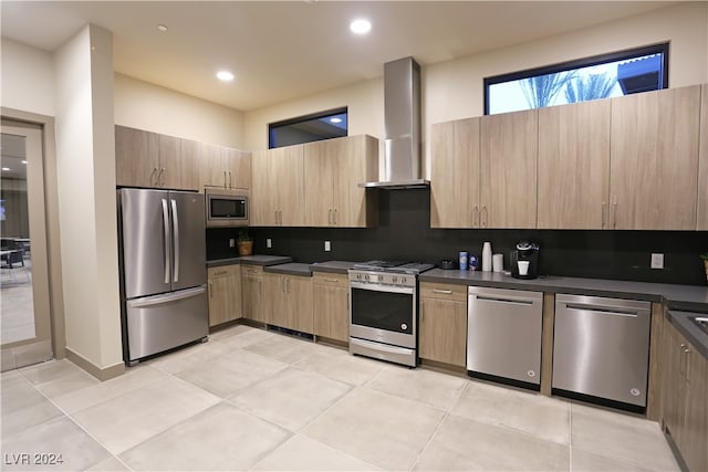 kitchen with decorative backsplash, light tile patterned floors, stainless steel appliances, and wall chimney exhaust hood