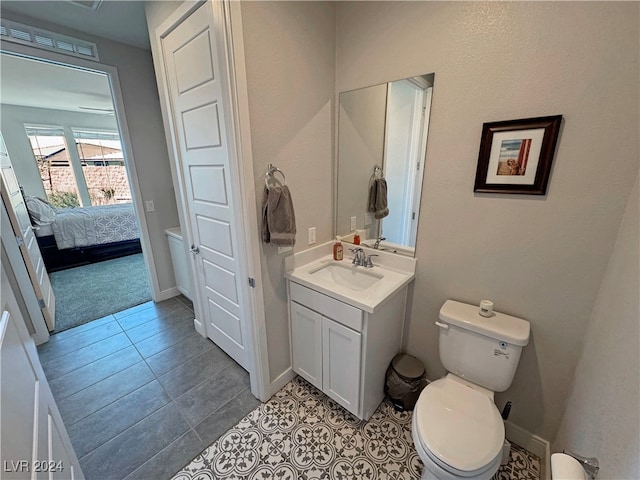 bathroom with toilet, vanity, and tile patterned floors