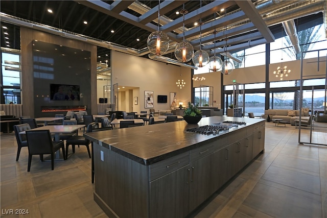 kitchen featuring a high ceiling, a water view, a spacious island, decorative light fixtures, and stainless steel gas cooktop