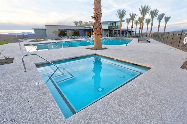 pool at dusk featuring a mountain view and a patio area