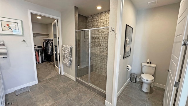 bathroom featuring tile patterned flooring, toilet, and a shower with shower door