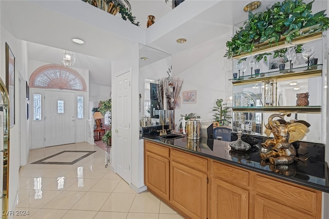 bar featuring vaulted ceiling, light tile patterned floors, dark stone countertops, and sink